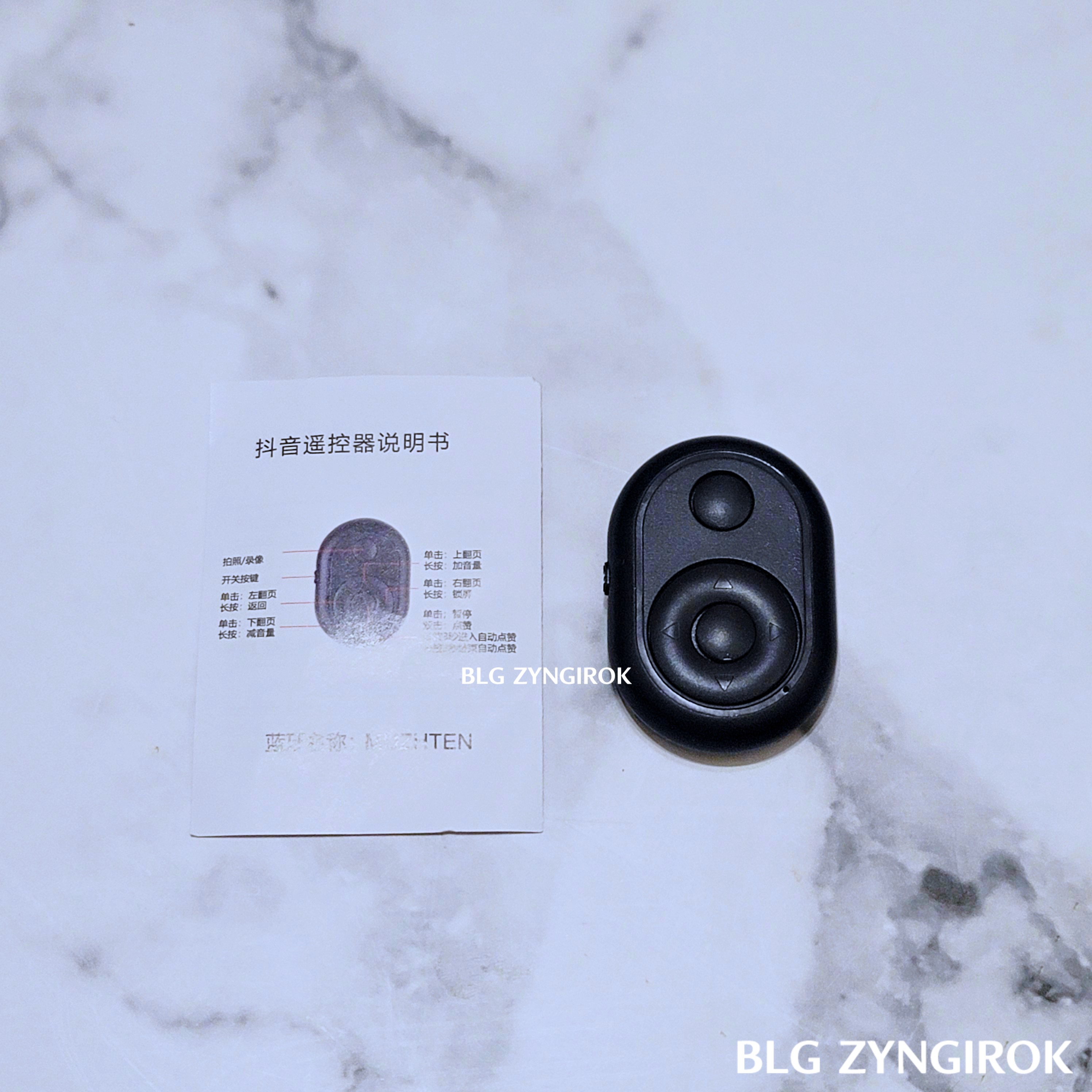 알리익스프레스에서 구매한 블루투스 리모컨 구성품인 설명서와 본 제품이 테이블 위에 놓여있다.