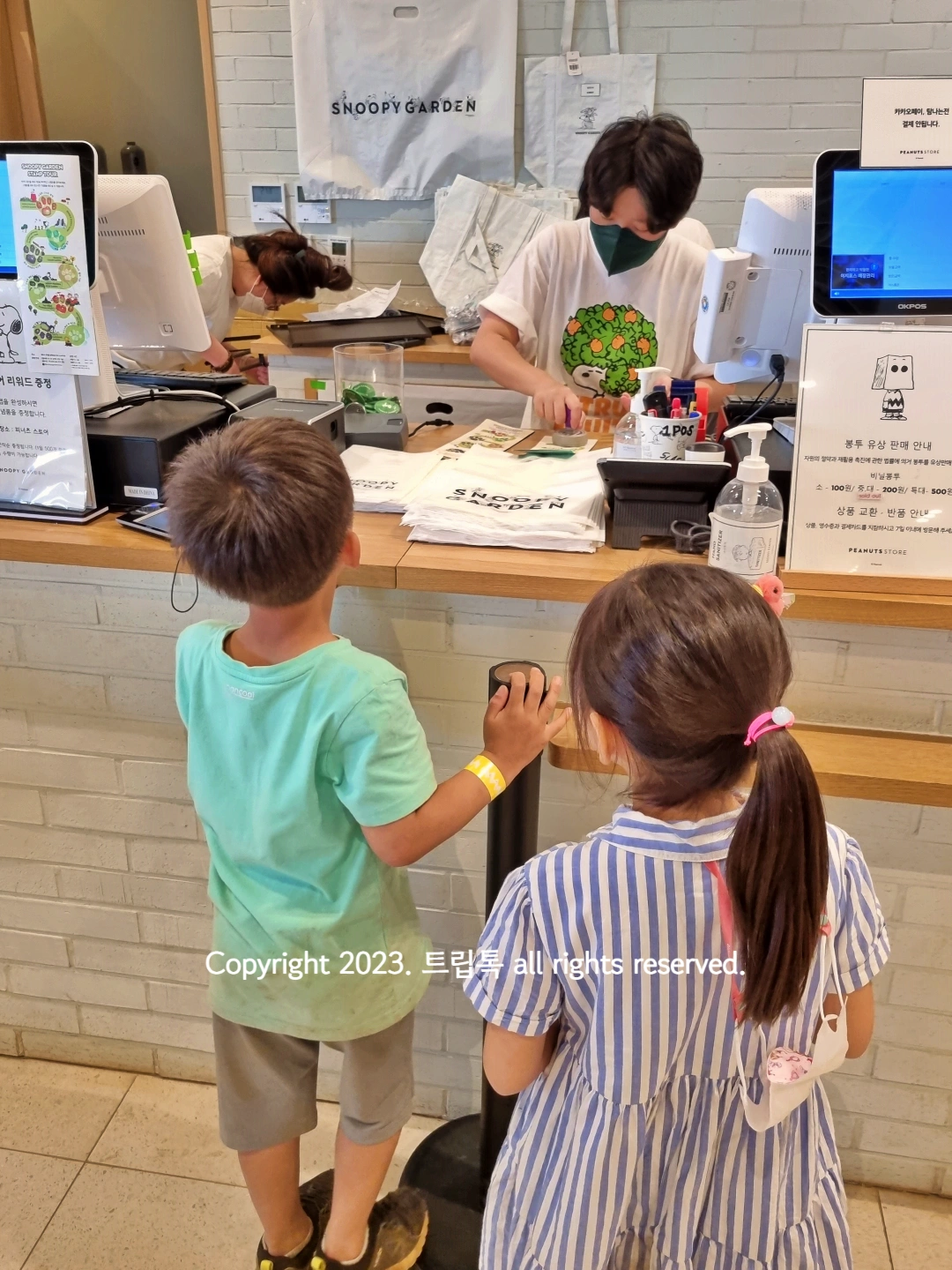 계산원이 물건을 포장하고 아이들이 기다리고 있다