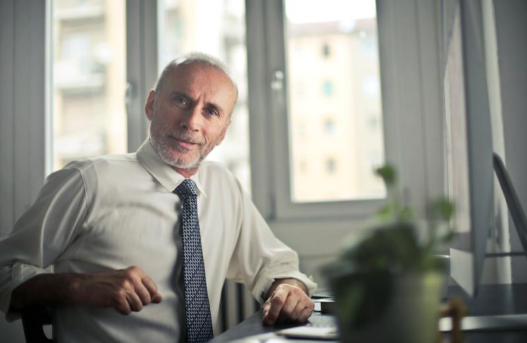 양복을 차려입은 중년 남성이 미소를 짓고 있다.