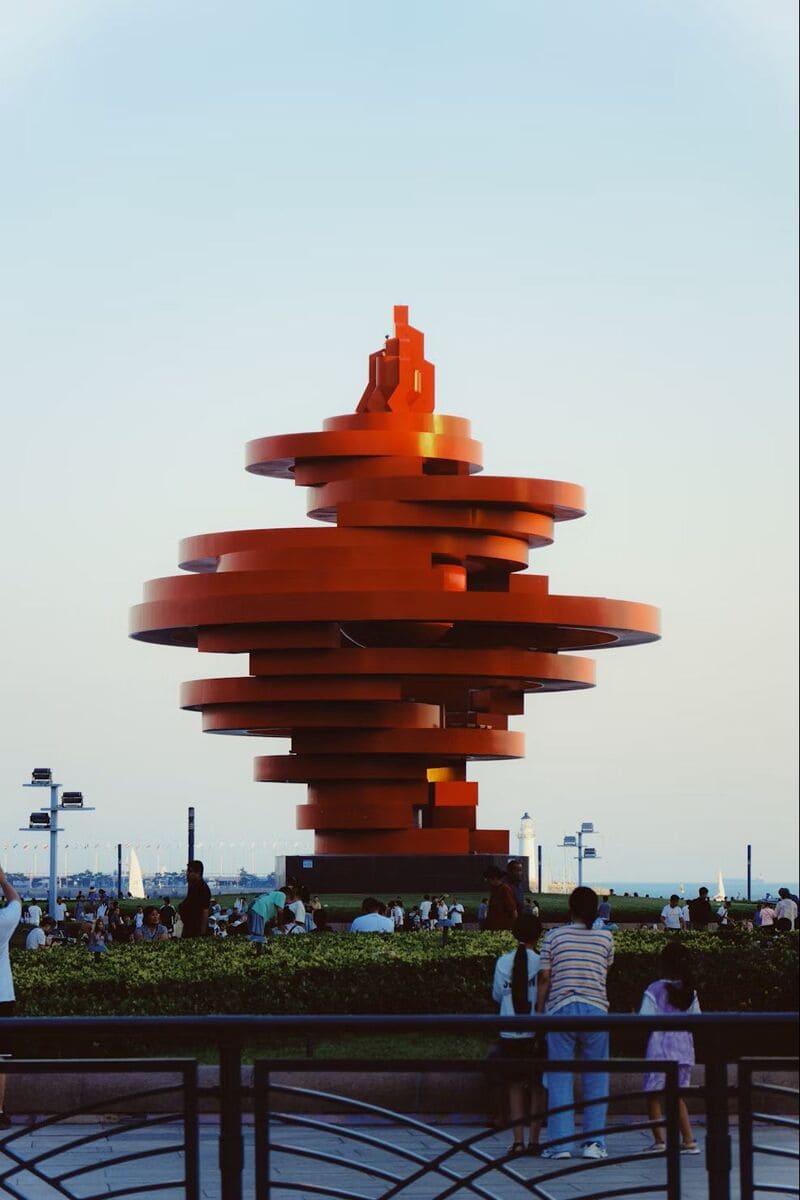 칭다오 5.4광장의 상징, 붉은 조형물 ‘오사광장 조각상’을 중심으로 사람들이 모여있는 풍경