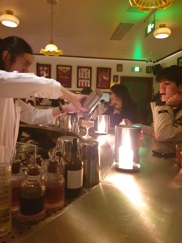 칵테일을 만들고 있는 바텐더와 그것을 바라보고 있는 손님