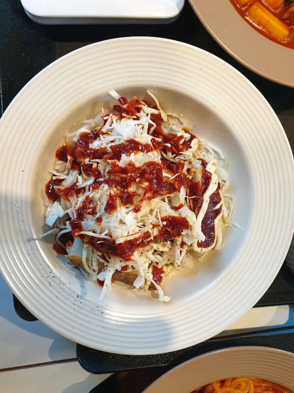 만두 위에 소스가 뿌려진 양배추가 올려져 잇는 4세대 만두