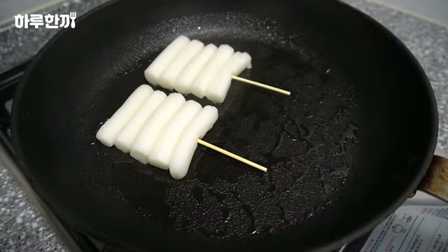 팬에 떡 꼬치를 올려 굽는 장면