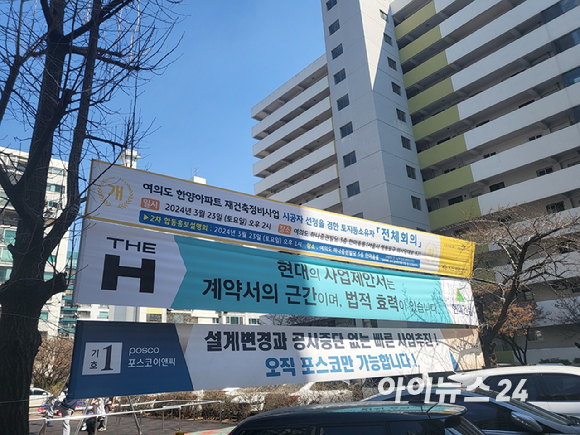 21일 서울 영등포구 여의도 한양아파트 단지 내 걸린 조합총회 개최 현수막과 현대건설&middot;포스코이앤씨 홍보 현수막 [사진=이수현 기자]