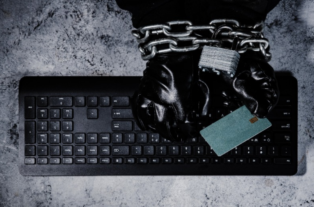 키보드 위에 쇠사슬을 찬 검은 손이 놓여있다.