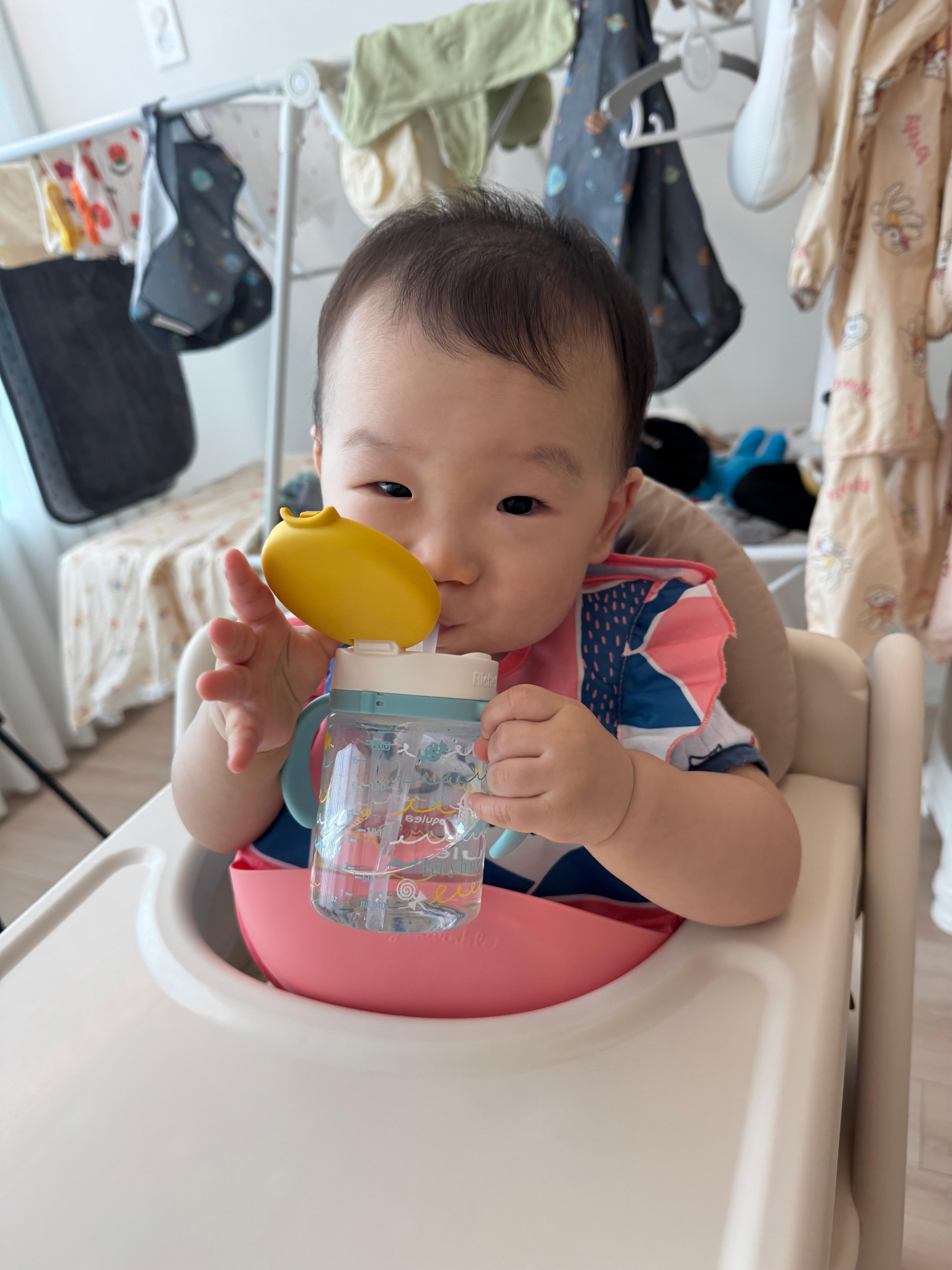 기분 좋은 미소를 지으며 물을 먹고 있는 아기