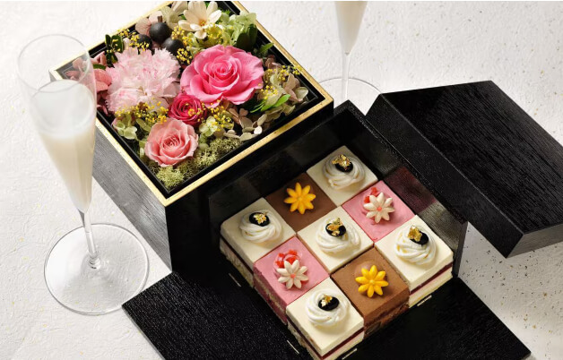 우아하게 꾸며진 꽃과 디저트 세트. 상자에 담긴 정교한 케이크와 장식된 꽃다발