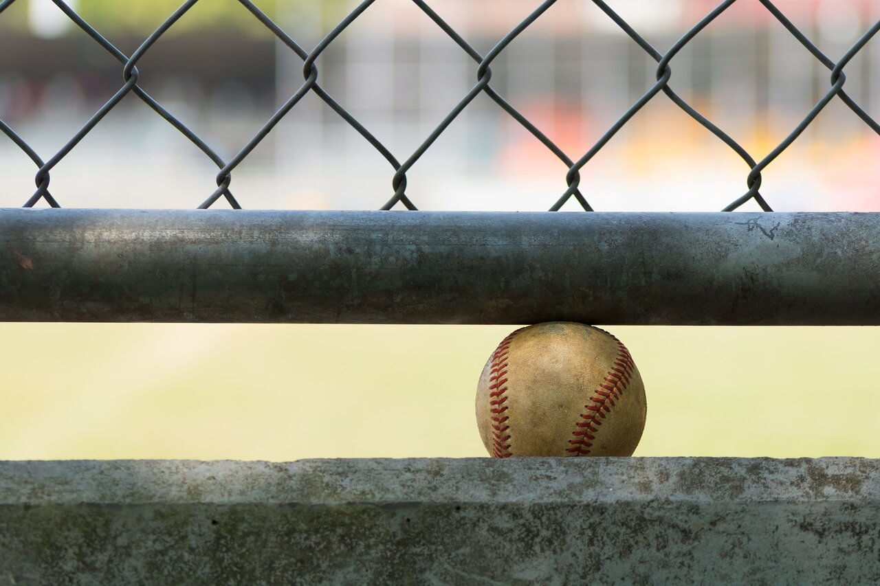A youth baseball player practicing hitting off a tee inside a home-built batting cage.