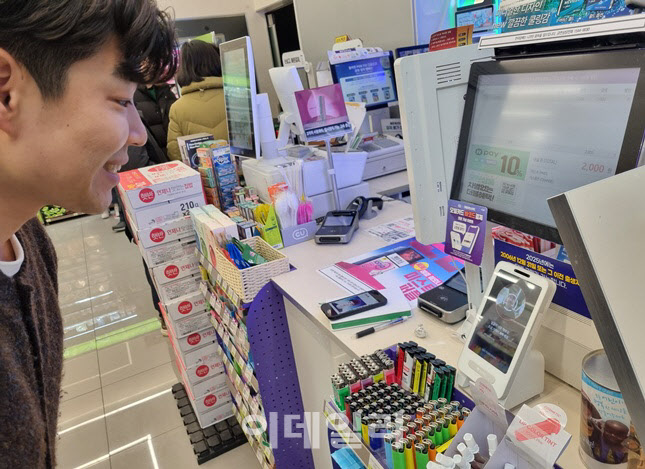 한 BGF직원이 과장된 웃음을 지어보이며 얼굴 결제 정확도를 테스트 하고 있다.