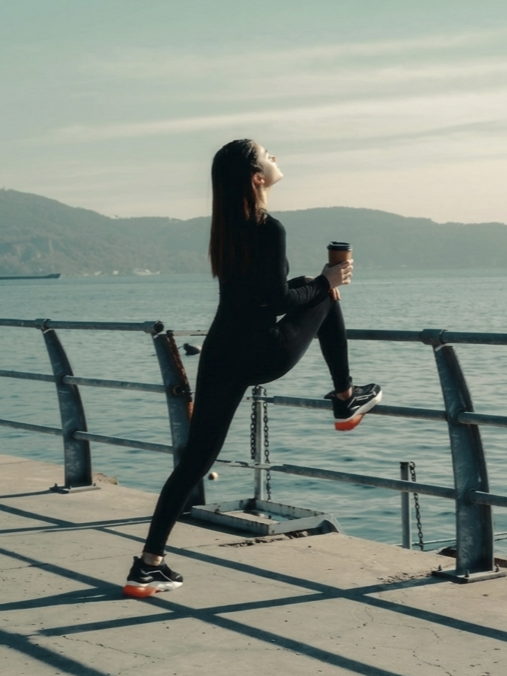 강변에 다리를 올리고 운동을 하며 커피를 마시는 사람