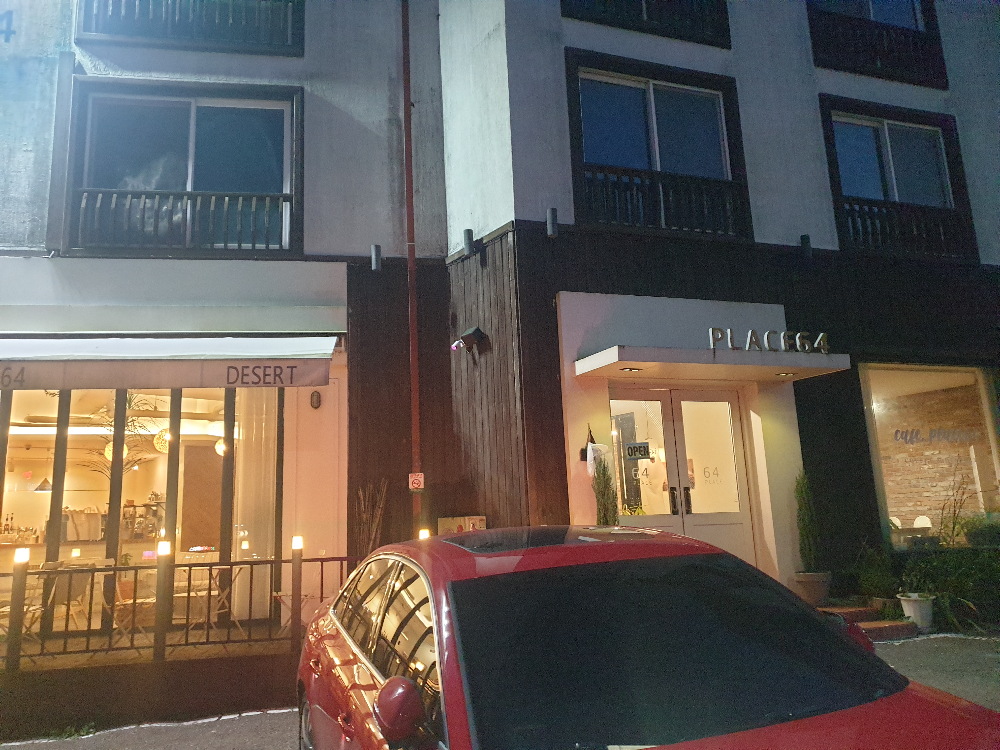 3층 건물에 1층만 환하다. 폴딩도어와 테라스가 있는 카페 앞에 붉은 차가 한 대 서있다.