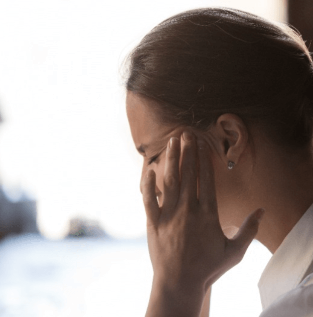 두통으로 괴로워하며 관자노리를 누르고 있는 젊은 여성의 모습