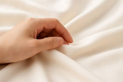 부드러운 천 위를 손끝으로 살며시 만지는 질감 중심 클로즈업