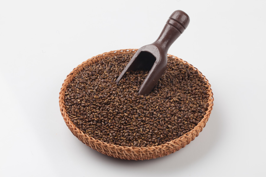 야생에서 채취를 한 결명자를 깨끗하게 세척한 후에 하얀 바닥 위에 대나무로 만든 동그란 바구니에 가득 담아두고 가운데에 갈색 나무 숟가락을 꼿아 놓고 찍은 사진