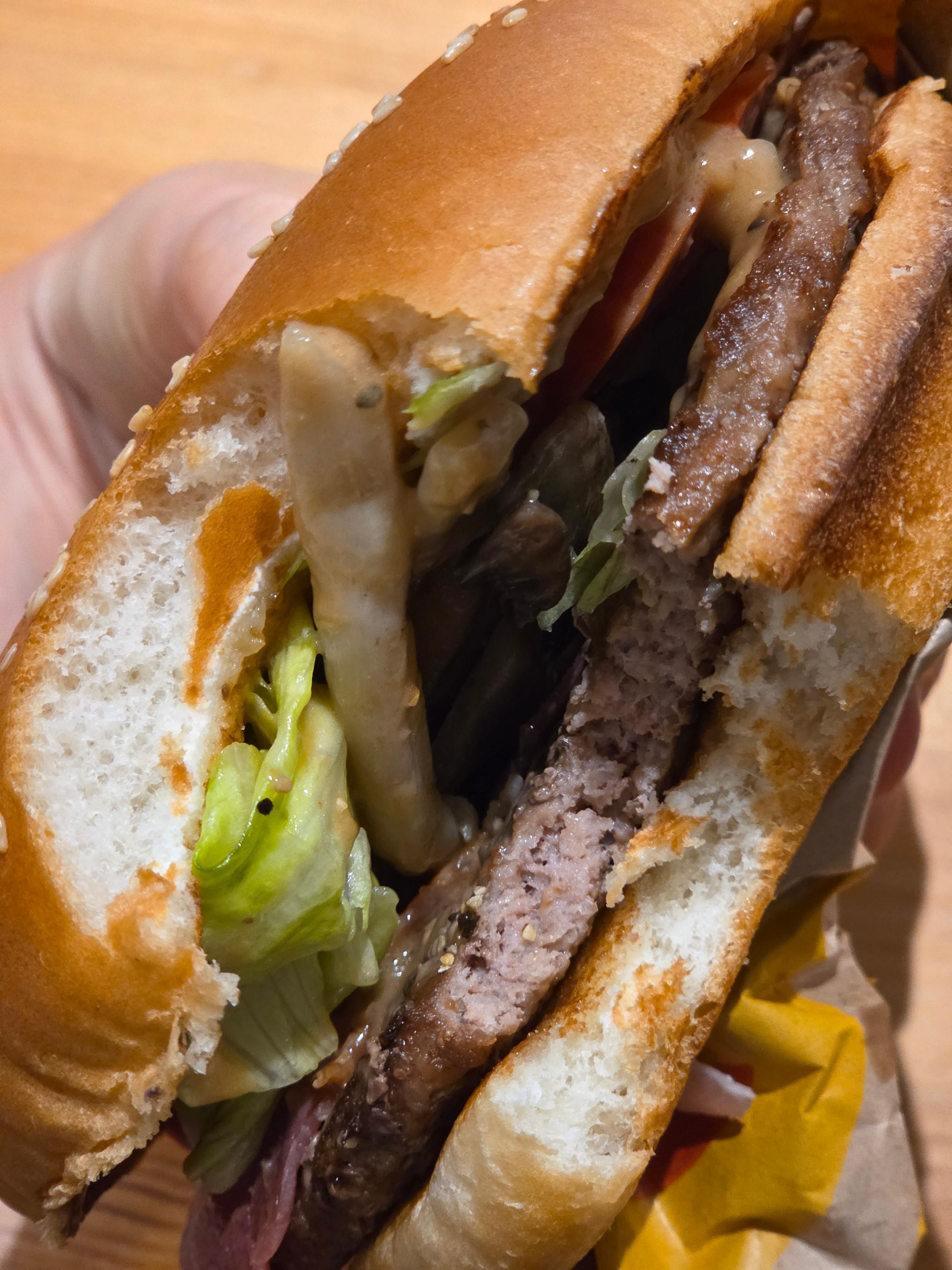 버거킹 트러플 머쉬룸 와퍼를 반으로 잘라 단면을 보여준 사진으로 패티와 토마토, 양상추, 버섯, 소스 층이 드러난 모습