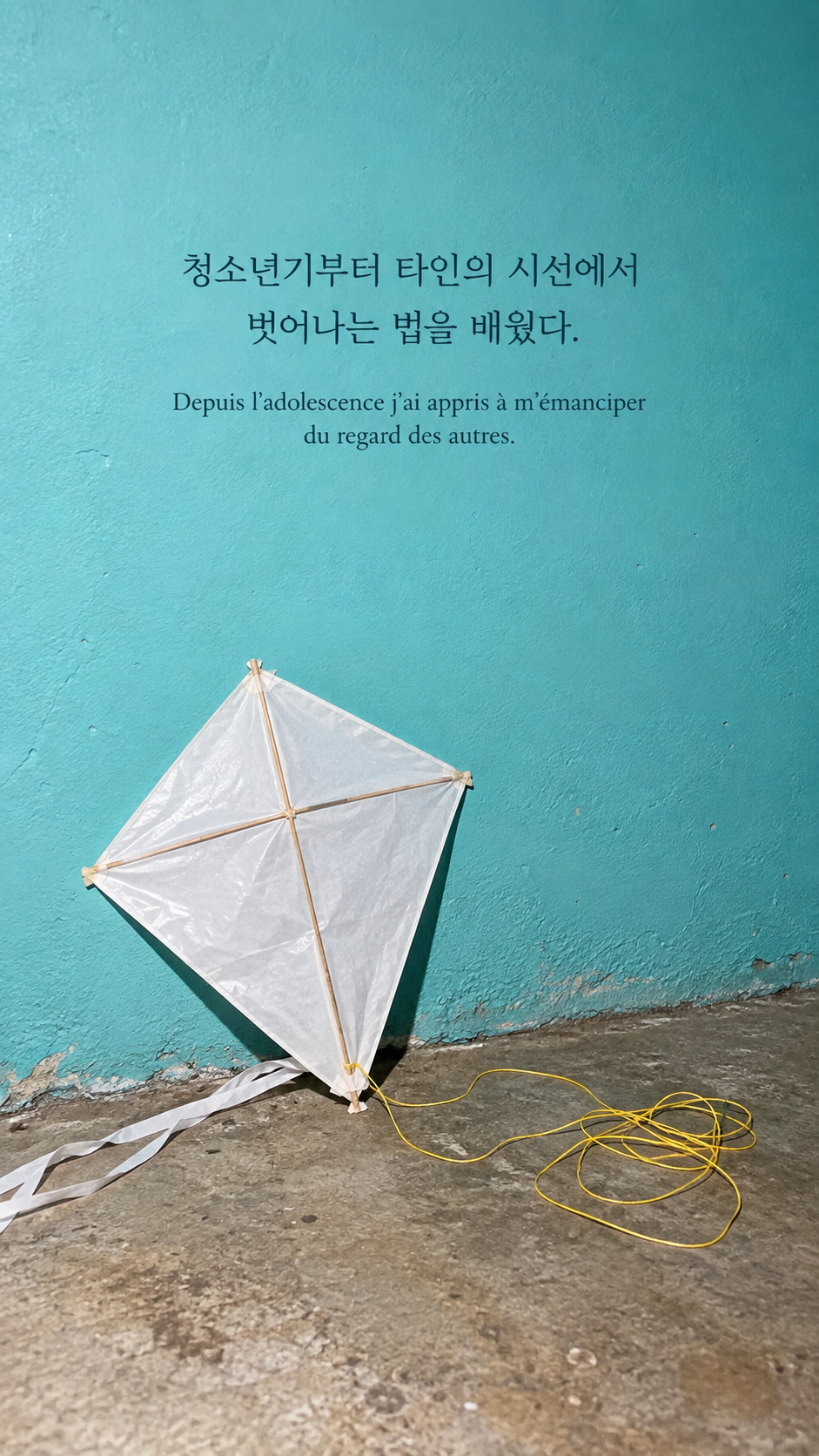 청록색 벽 앞의 흰 연 배경에 담은 기욤 뮈소의 말: 청소년기부터 타인의 시선에서 벗어나는 법을 배웠다.