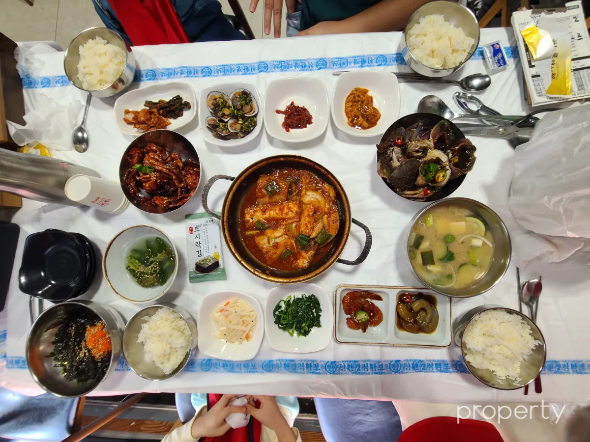 상위에-흰색비닐-가운데-갈치조림-양옆에-간장게장-양념게장-8가지밑반찬-맑은된장국-물김치-밥4개-날치알버터세트2개