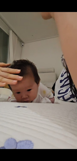 엄마의응원을 받으며 침대위에서 터미타임을 하고있는신생아