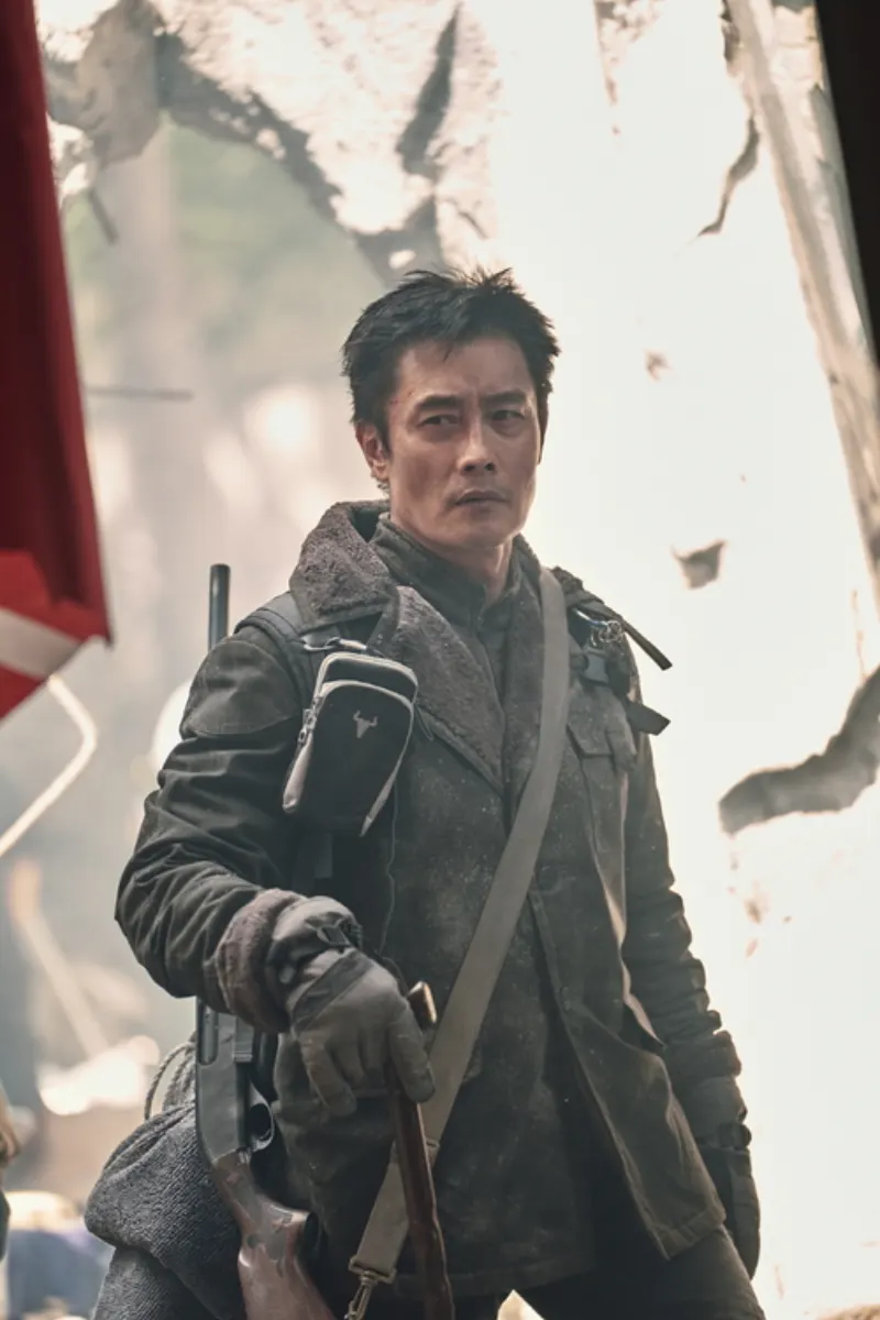 폐허가 된 건물 속에서 겨울 코트를 입고 서있는 김영탁