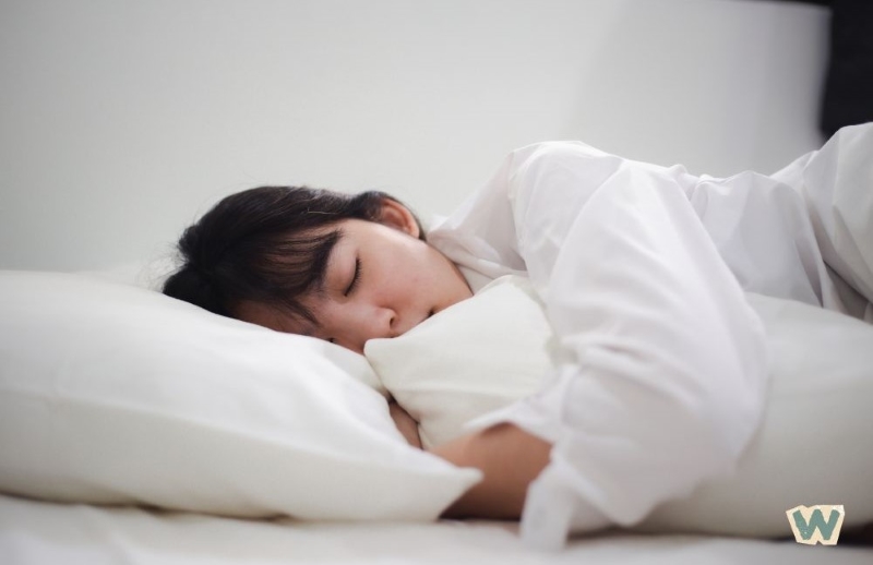 편안하게 잠들어 있는 여성의 모습, 흰색 침구와 베개에서 숙면을 취하고 있는 장면 via canva