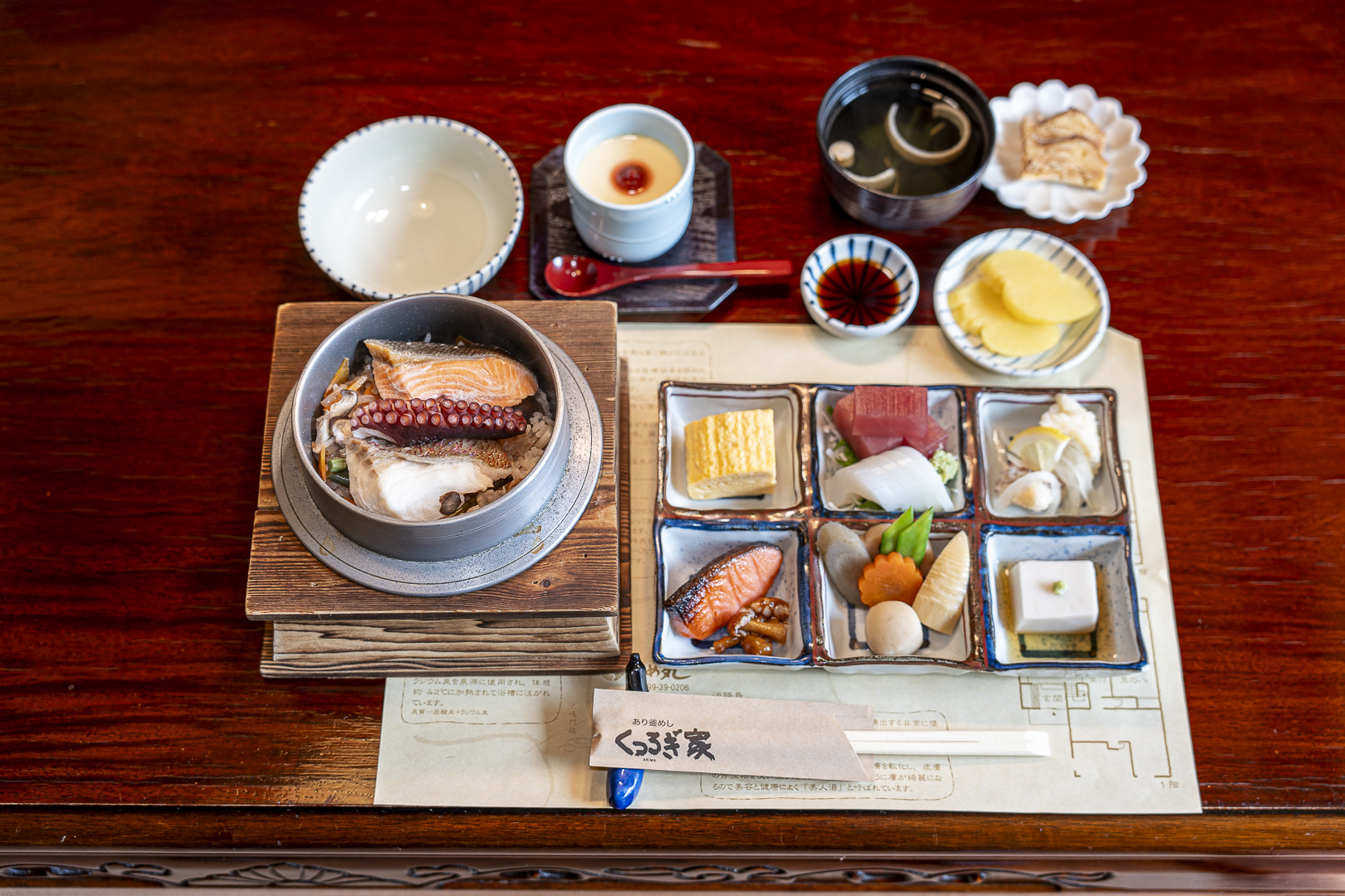 Pot-cooked rice and side dishes on a wooden tray at Kutsurogiya