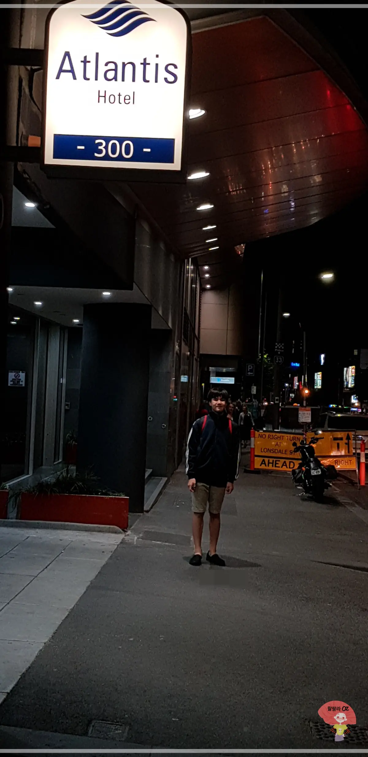 호주-멜버른-아틀란티스-호텔-앞-밤-거리-조카-검은-재킷-반바지-입고-서있는-모습