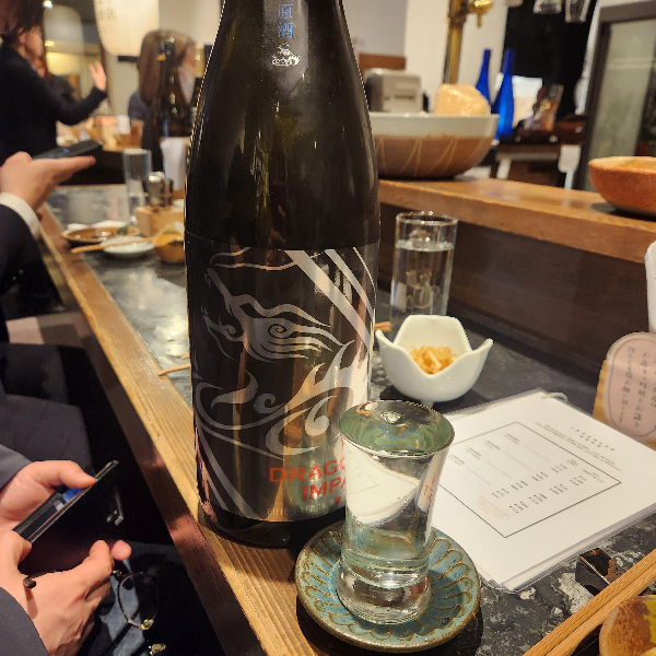 검은색 병과 사케가 가득 담긴 잔이 보인다.