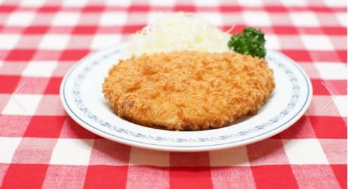 흰 접시 위에 돈까스가 올려져 있다.