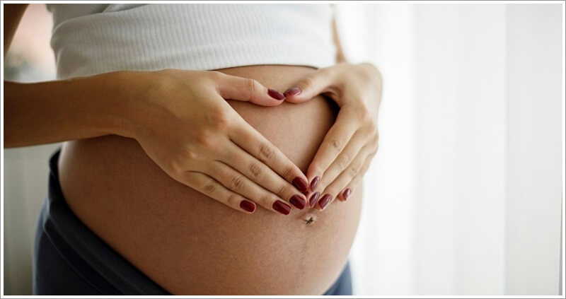 배 나온 임신한 여자가 배에다 손을 올리고 하트 그림을 하고 있는 사진