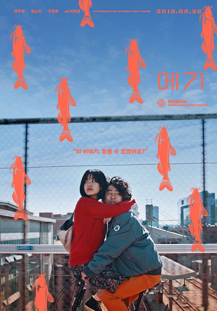 메기 영화 포스터, 이주영과 구교환이 자전거를 같이 타고 지나가고 있다. 메기 모양의 그림이 포스터에 그려져 있다.
