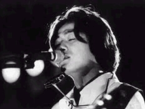 장발의-김광석이-하모니카를-목에-걸고-눈을-감고-마이크에-노래를-부르는-흑백-사진