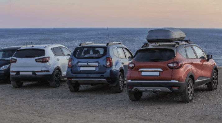 “해변가에 주차된 다양한 색상의 SUV 차량들, 일몰을 배경으로 한 장면