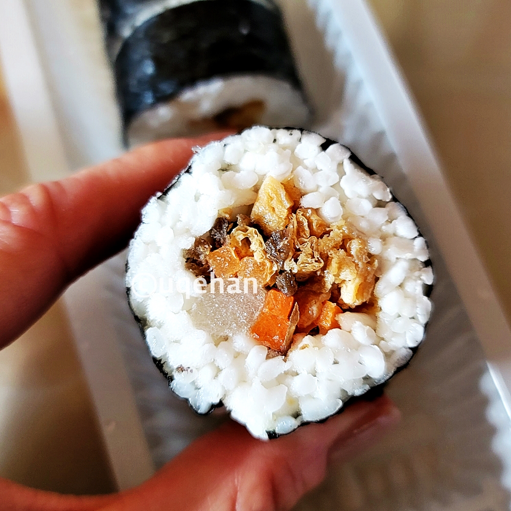 노브랜드 든든한 한끼 유부우엉김밥을 손가락을 집어 들고 있다.