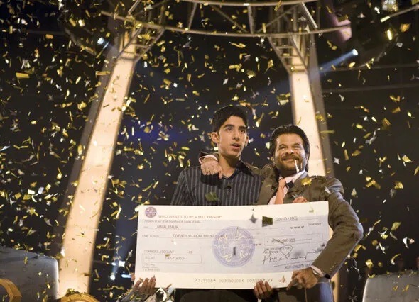 영화 《슬럼독 밀리어네어》에서 자말이 퀴즈쇼 우승을 통해 인생 역전의 순간을 맞이하는 장면. 눈부신 조명과 축포 속에서도, 그의 눈동자엔 믿기지 않는 현실과 삶의 무게가 담겨 있다.