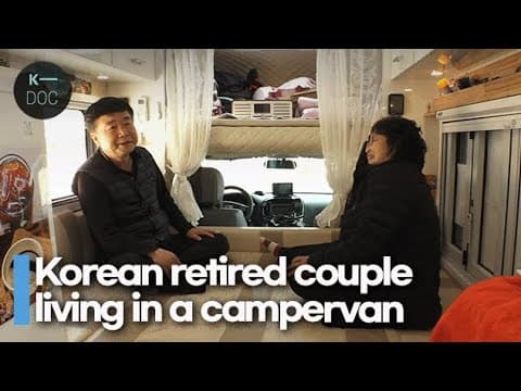 캠핑카 안의 모습으로 좌석 뒤편에 하얀 커텐을 달아 안쪽에 방과 구별하고, 양쪽으로 묶어 운전석 앞 유리창이 보인다, 좌식으로 만든 방안에 부부가 마주 보고 앉아 있는 이미지