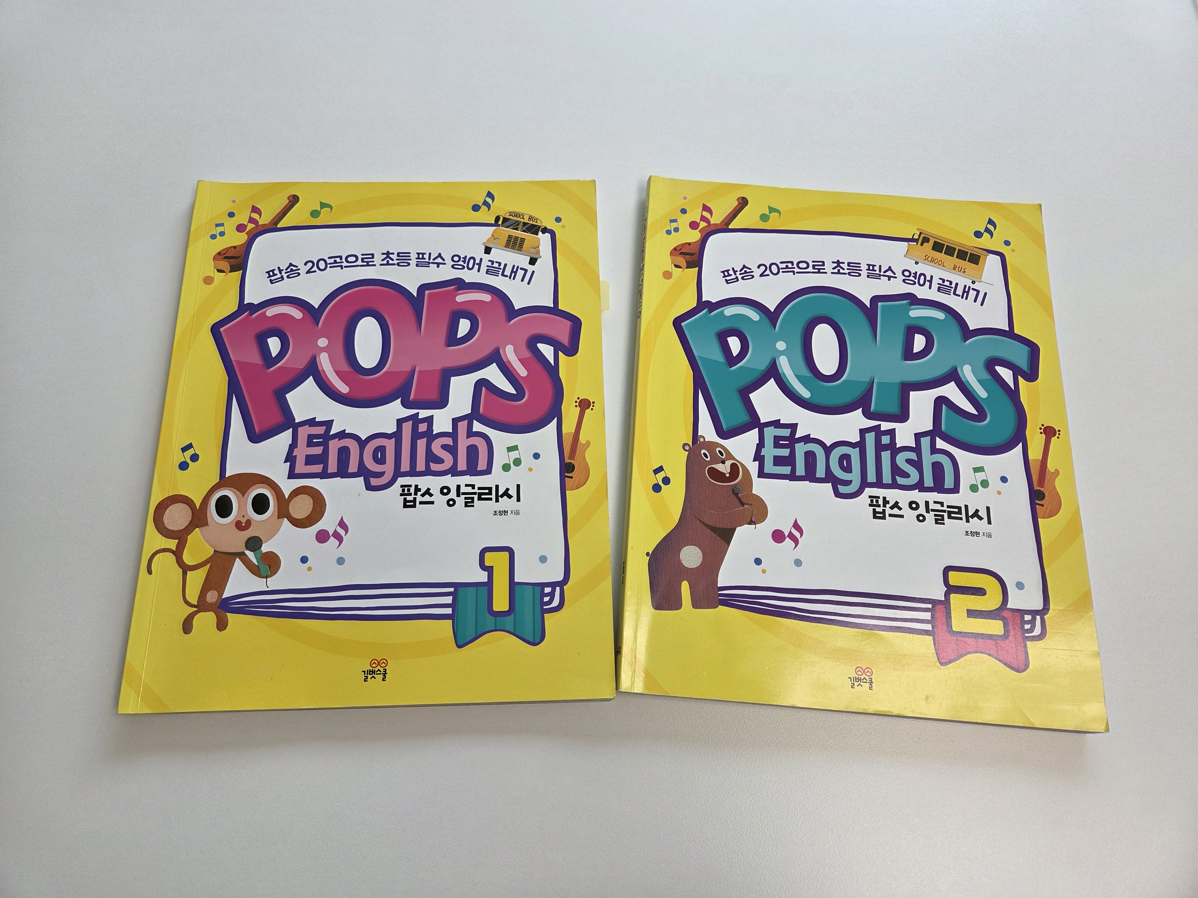 왼쪽은 팝스잉글리쉬 1권, 오른쪽은 팝스 잉글리쉬 2권 표지가 책상에 놓여있어요.