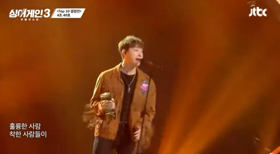 싱어게인3-
갈색배경 베이지색 쟈켓에 탬버린을 치며 검은색 스탠딩 마이크에 노래하는 40호