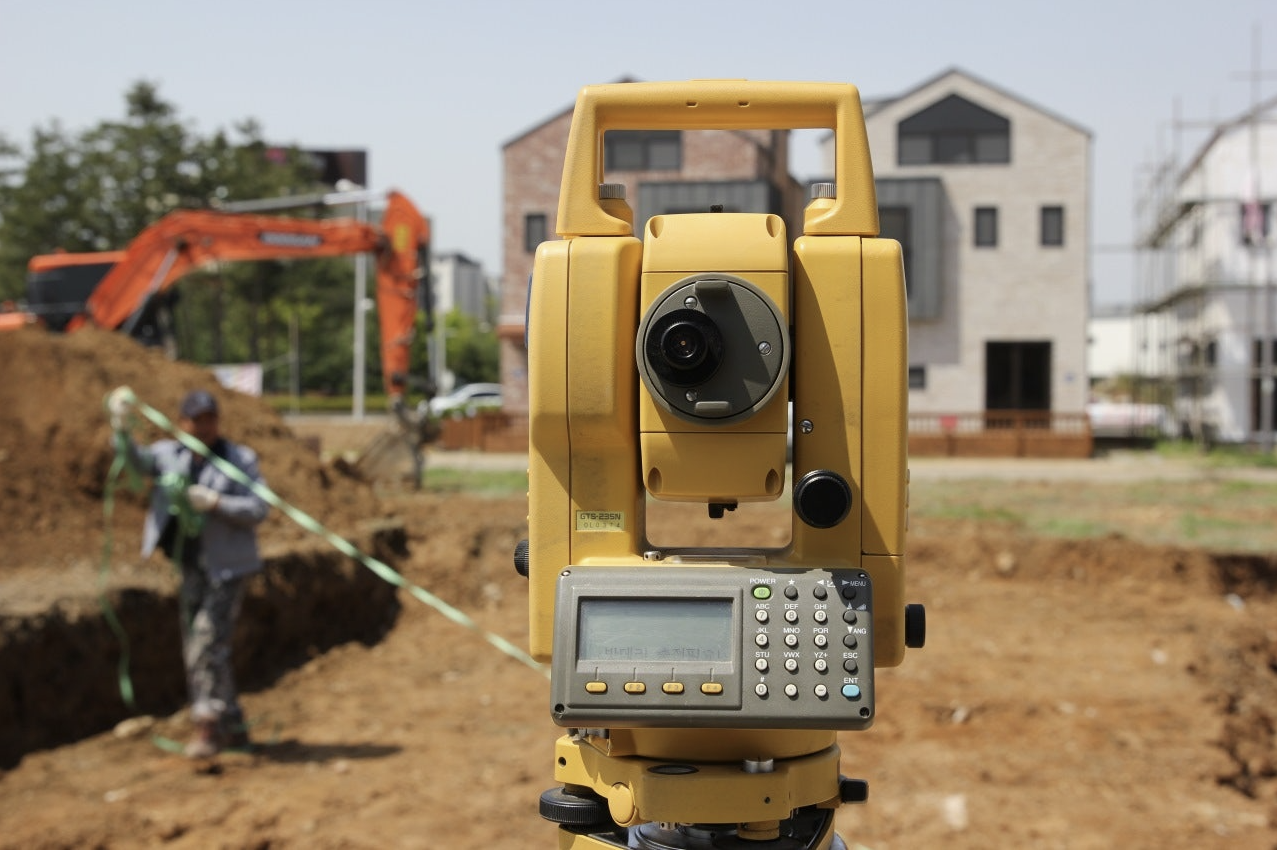토지 계약 전 땅의 정확한 경계 구분을 위해 측량하고 있는 모습