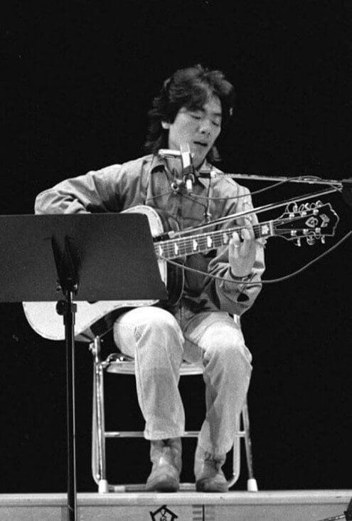 김광석이-무대위에-앉아-기타를-치며-노래를-부르고-있는-흑백-사진