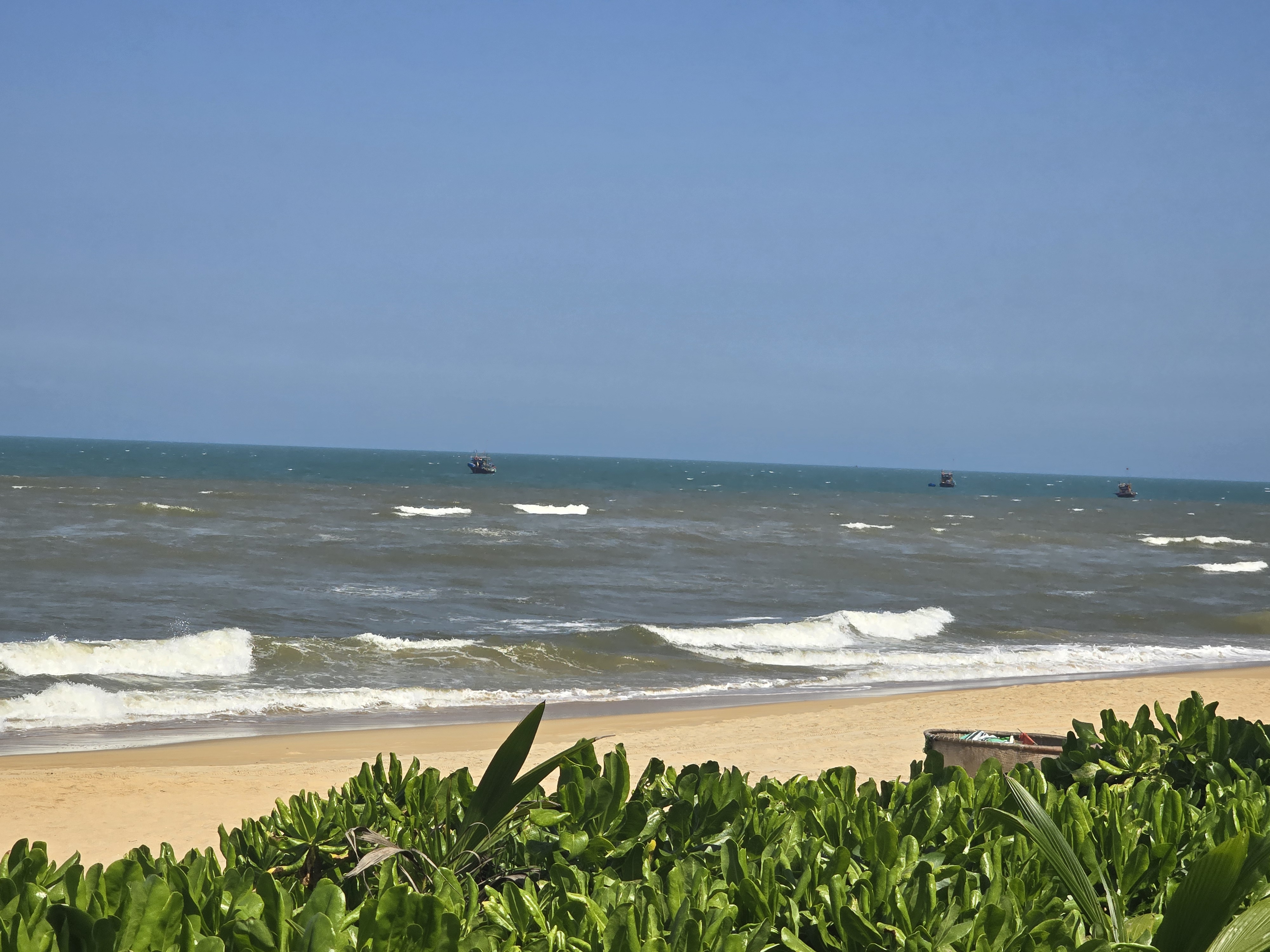 땀끼 해변 파도와 멀리 떠 있는 어선들이 보이는 바다 풍경