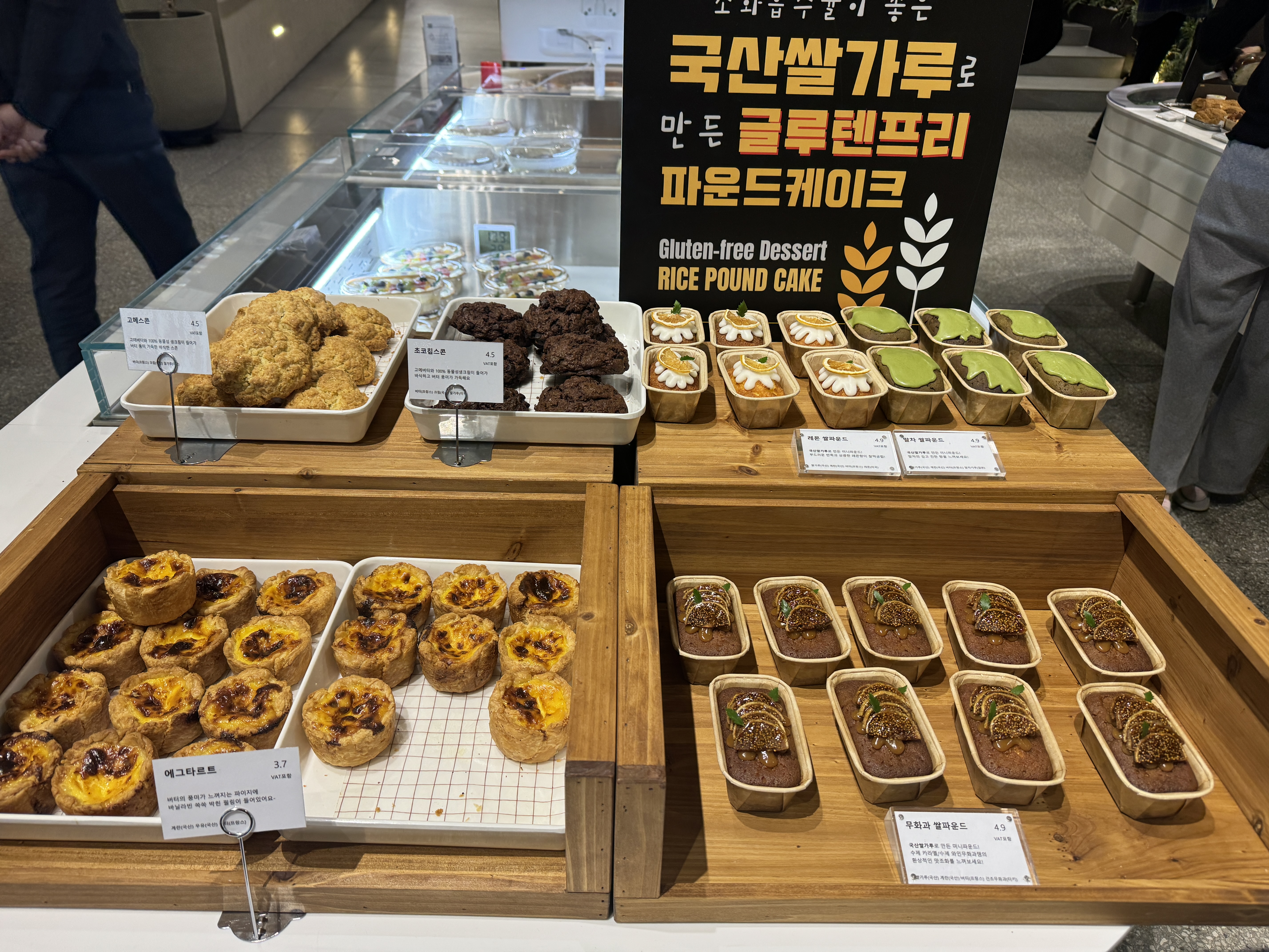 동탄 카페 아스타나 베이커리 진열대&amp;#44; 국산 쌀가루로 만든 글루텐프리 파운드케이크와 말차&middot;초콜릿 디저트가 나무 트레이 위에 전시된 모습