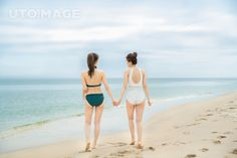 수영복을-입고-하얀-백사장을-손을잡고-걸어가는-여성