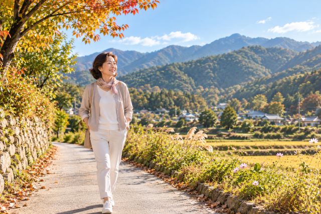가을 아침 산이 보이는 시골 길을 가볍게 산책하는 중년 여성