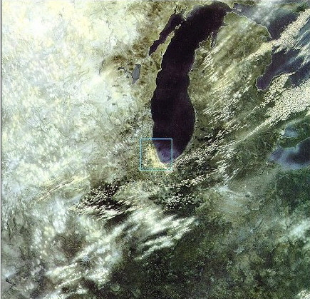 지상 1,000킬로미터 상공에서 바라본 북미 대륙 중부. 화면 중앙에는 미시간 호수가 검푸른 빛으로 뚜렷하게 보이며, 그 남서쪽 끝에 시카고가 점처럼 위치해 있다. 주변으로는 오대호의 일부와 넓은 숲과 구름들이 펼쳐져 있으며, 인간의 흔적은 거의 보이지 않을 정도로 작아진다. 지구의 곡률과 대기의 질감이 은은히 드러나는 시점이다.