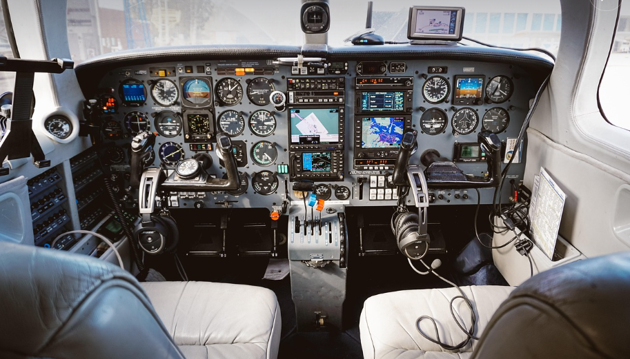 비행기 조종석 내부의 복잡한 계기판과 조종 장치 모습, 영화 '굿뉴스'의 주요 배경과 유사한 분위기를 담고 있음