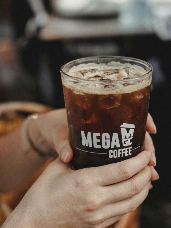 두 손으로 메가커피의 아이스 아메리카노를 들고 있는 모습