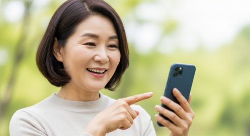 중년 여성이 웃으며 스마트폰을 가리키는 장면