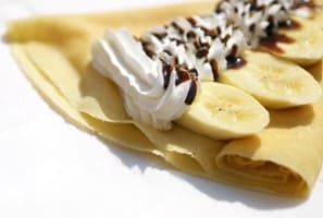 노란색 구운 반죽위에 흰색 크림과 바나나가 올라가 있다.