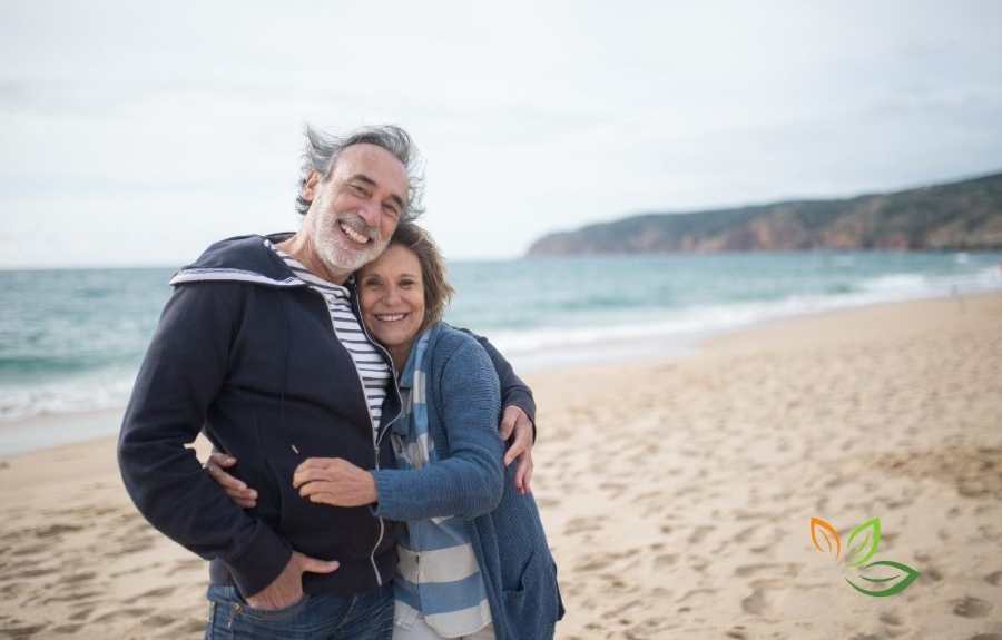 해변에서 행복하게 포옹하고 있는 중년 부부, 건강한 중년 라이프스타일과 성공적인 다이어트 후의 활력 넘치는 모습을 보여주는 이미지 via canva