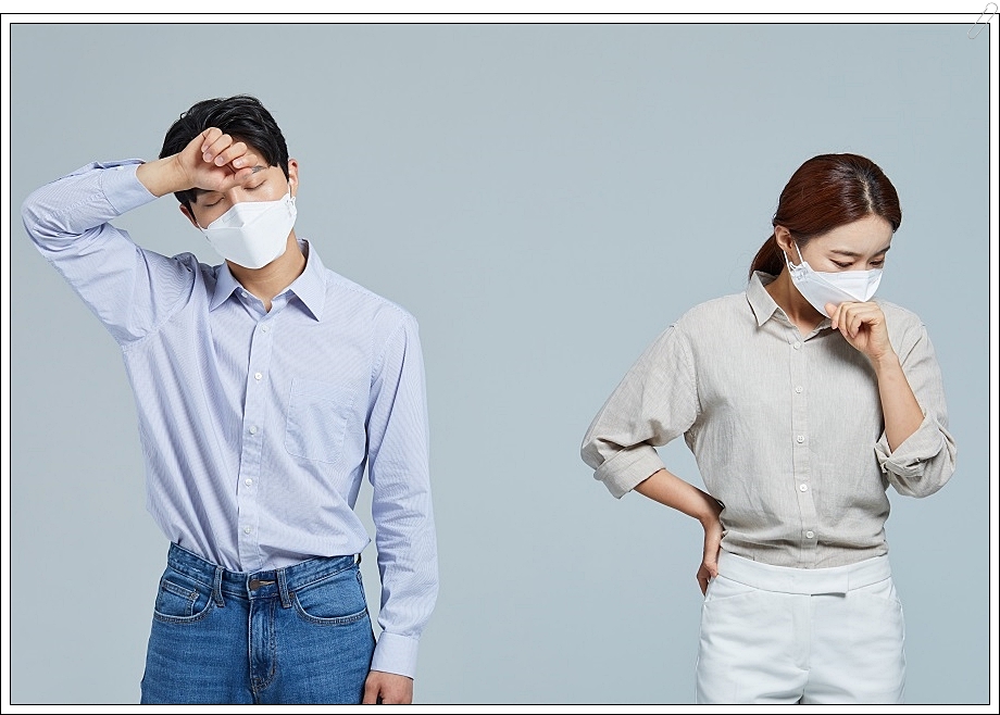 마스크를 낀 남녀가 각각 이마와 입가에 손을 가져다 댄 채 다소 힘든 표정을 짓고 있는 모습